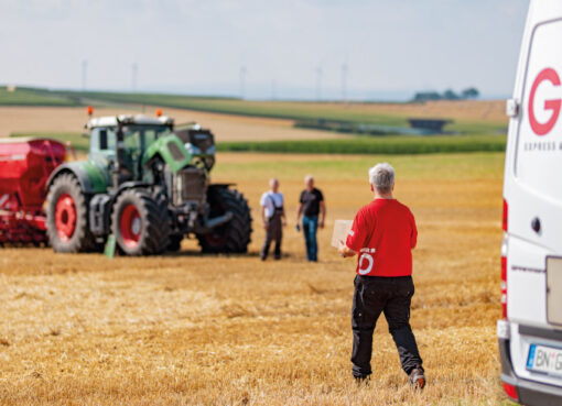 Lieferfahrzeug beim Traktor auf dem Feld